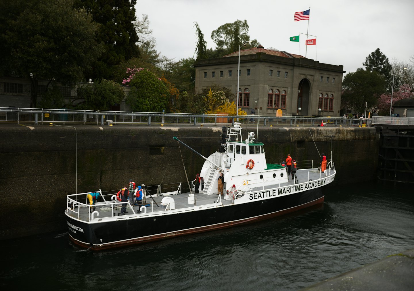 Studenti con giubbotti di salvataggio navigano su una nave dell'accademia marittima attraverso una chiusa.