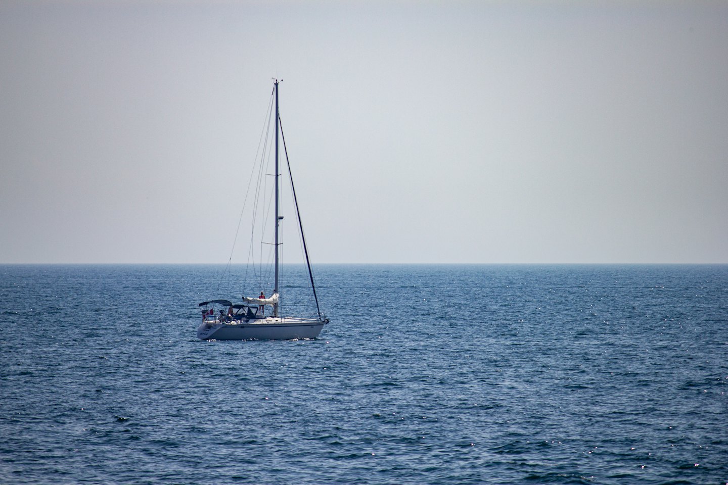 Una barca a vela con persone a bordo che naviga nell'oceano aperto.